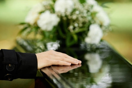 woman with hand on the casket of a loved one
